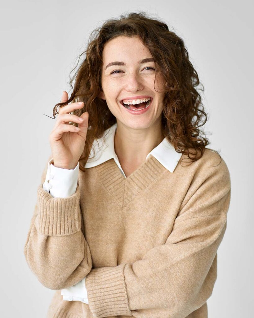 young happy cheerful woman standing at white backg U4VY5ST